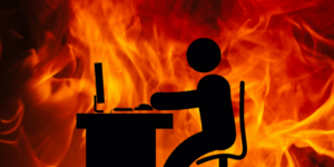 Silhouette of a person sitting at a desk with a background of flames