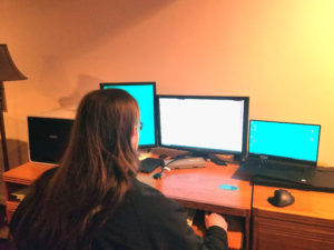 Mechanical Designer Luke Yount a facing three monitors in his home office space. 