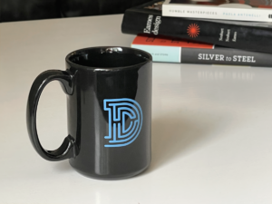 Daedalus coffee mug on desk with books int he background
