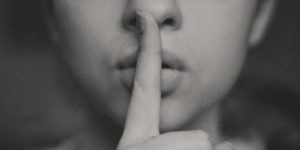 A person holding their index finger in front of their mouth in a "shhhh" motion